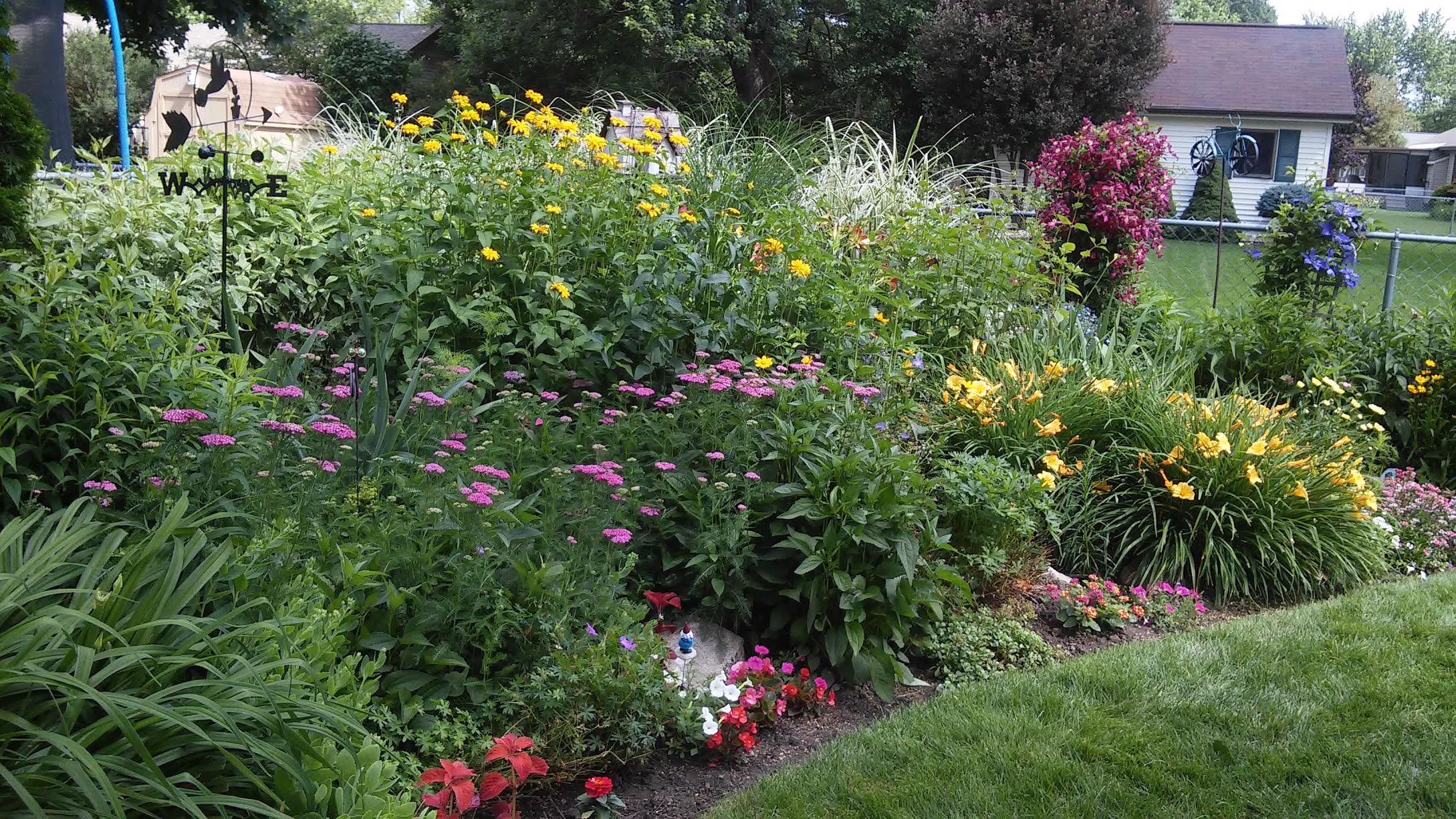 A flower bed with lots of colorful flowers next to a lawn